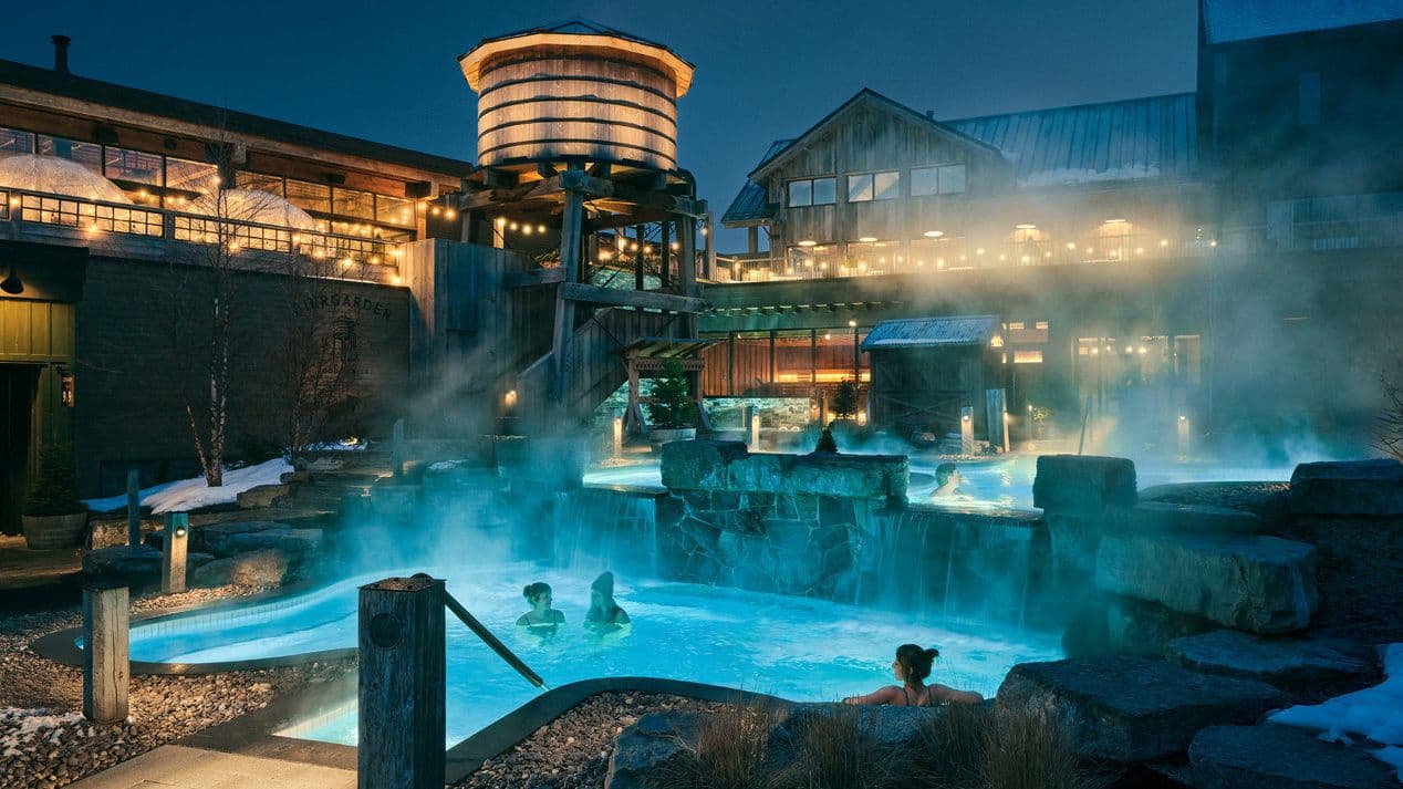 Guests relaxing in steaming outdoor thermal baths at Thermea Spa Village Whitby on a winter evening