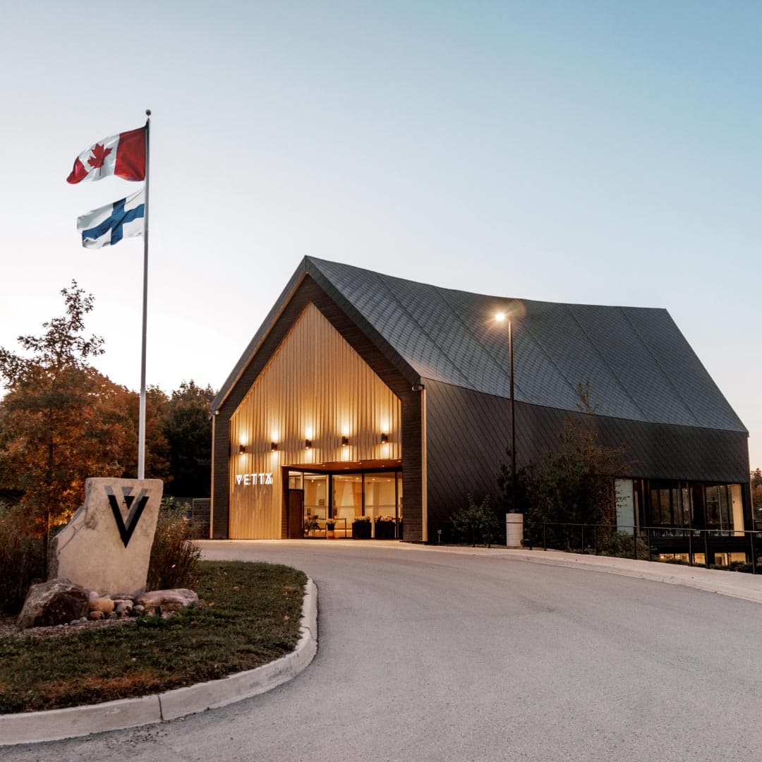 Exterior view of Vetta Nordic Spa at dusk showing the modern barn-style building with warm interior lighting