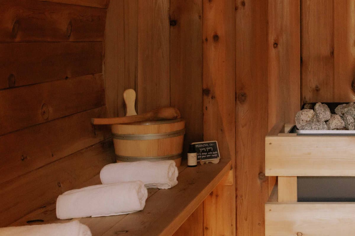 Gatherwell barrel sauna interior with cedar benches, towels, and heater stones